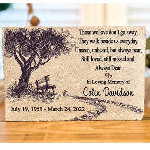 May include: A memorial stone with a drawing of a tree and a bench. The stone has the text "Those we love don't go away, They walk beside us everyday. Unseen, unheard, but always near, Still loved, still missed and Always Dear. In Loving Memory of Colin Davidson July 19, 1955 - March 24, 2022"