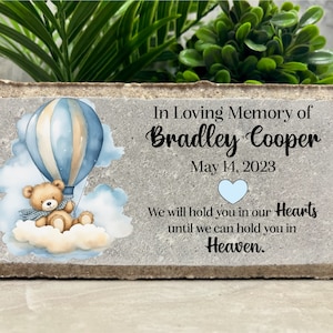 May include: A concrete memorial block with a blue and white hot air balloon, a teddy bear, and clouds. The text reads "In Loving Memory of Bradley Cooper May 14, 2023 We will hold you in our Hearts until we can hold you in Heaven."