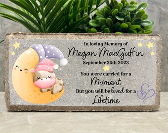 Può includere: Una pietra commemorativa in cemento grigio con un'illustrazione di luna gialla e una mucca che dorme. Il testo recita "In loving Memory of Megan MacGuffin 25 settembre 2023 Sei stato portato per un momento Ma sarai amato per tutta la vita"