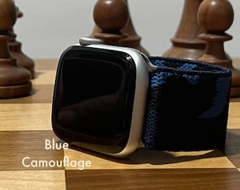 May include: A silver Apple Watch with a black and blue camouflage sport band. The watch face is black and the band has a blue and black camouflage pattern.