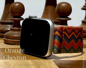 May include: A silver Apple Watch with a black screen and an orange, blue, and yellow chevron patterned band. The text "Orange Chevron" is visible below the watch.
