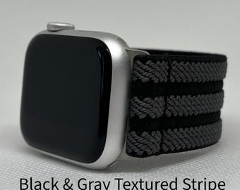 May include: A silver smartwatch with a black screen and a black and grey textured stripe band. The band features a repeating pattern of black and grey stripes. The text "Black & Gray Textured Stripe" is at the bottom of the image.