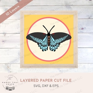 May include: A layered paper cut file of a blue and black butterfly with red accents. The butterfly is in a circle on a yellow background. The file is for use with a cutting machine and includes SVG, DXF, and EPS formats.