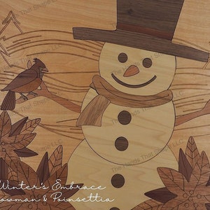 Puede incluir: Una obra de arte de madera que representa a un muñeco de nieve con un cardenal posado en una rama. El muñeco de nieve lleva un sombrero marrón y una bufanda. El fondo es un patrón de veta de madera con el texto "Winter's Embrace Snowman & Poinsettia".