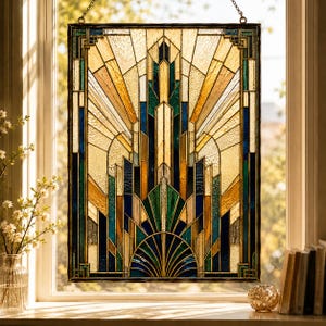 Op de afbeelding: Een rechthoekig glas-in-loodpaneel met een geometrisch patroon van verticale lijnen en waaiervormen. Het glas bestaat uit amberkleurige, diepblauwe en smaragdgroene segmenten die door donkere metalen profielen worden vastgehouden en aan een ketting hangt.
