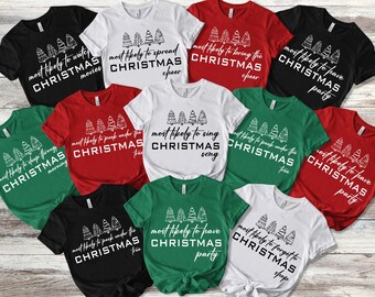 May include: A collection of short-sleeved t-shirts in black, white, red, and green. Each shirt features a graphic of four hand-drawn Christmas trees above text that reads "most likely to" followed by various holiday-themed phrases in black or white.