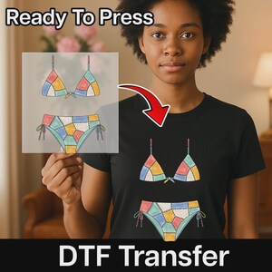 May include: A black t-shirt featuring a graphic of a patchwork bikini set with blue, yellow, pink, and green segments. The design includes a triangle top and side-tie bottoms. The text Ready To Press and DTF Transfer is visible.