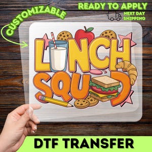 May include: A colorful DTF transfer featuring the words "LUNCH SQUAD" with illustrations of a glass of milk, sandwich, apple, cookies, and a pencil. The design is ready to apply and customizable.