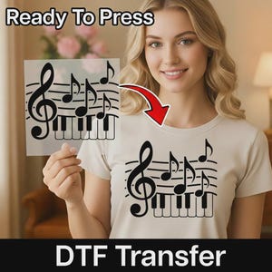May include: A DTF transfer sheet featuring a black graphic of a treble clef, musical notes, and piano keys. The same design is applied to a beige t-shirt. The text Ready To Press is at the top, and DTF Transfer is at the bottom of the image.