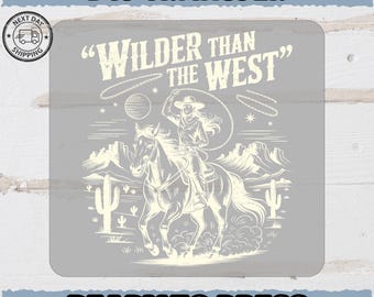 Może przedstawiać: Szary transfer DTF z ilustracją w stylu vintage przedstawiającą kowbojkę na koniu, rzucającą lasso. Tekst "Wilder Than The West" znajduje się nad kowbojką. Słowa "Ready To Press" znajdują się na dole.