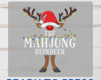 May include: A DTF transfer featuring a reindeer design with a Santa hat and string lights. The text reads "The Mahjong Reindeer" and "Ready to Press" in blue. The design is on a gray background.
