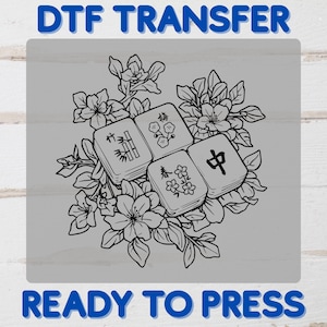 May include: A black and white DTF transfer design featuring four Mahjong tiles surrounded by floral elements. The tiles display various symbols and characters. The text "DTF TRANSFER" and "READY TO PRESS" are in blue.