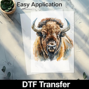 May include: A watercolor-style DTF transfer featuring a detailed bison illustration. The artwork showcases the animal's brown fur, horns, and facial features. The text "Easy Application" is at the top, and "DTF Transfer" is at the bottom.