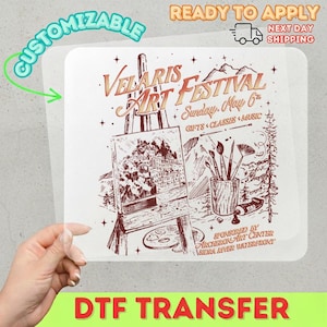 May include: A DTF transfer featuring the text "Velaris Art Festival" with an illustration of an easel, brushes, and a landscape painting. The transfer is customizable and ready to apply.