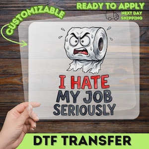 May include: A clear DTF transfer sheet featuring a cartoon illustration of an angry toilet paper roll with a sweating, frustrated expression. Below the character, the text reads I HATE MY JOB SERIOUSLY in bold red and black lettering.