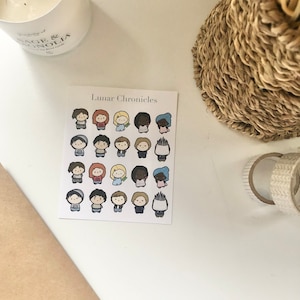 May include: A sheet of stickers featuring 20 different characters from the Lunar Chronicles book series. The stickers are colorful and feature a variety of characters with different hairstyles and clothing.