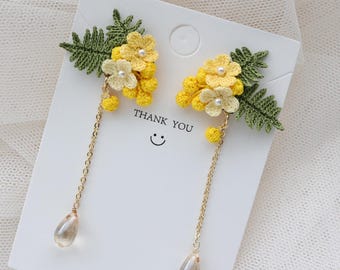 May include: A pair of yellow and green crocheted flower earrings with a gold chain and a clear teardrop crystal dangle. The earrings are displayed on a white card with the text "Thank You" and "Fashion Accessories".
