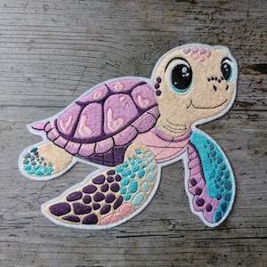 Può includere: Toppa ricamata di una tartaruga marina dei cartoni animati. La tartaruga presenta un guscio viola, pinne rosa e blu e un viso beige con grandi occhi neri. La toppa ha un bordo bianco ed è ambientata su uno sfondo di legno.