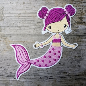 May include: Pink embroidered mermaid patch with a white outline. The mermaid has pink hair, a pink top, and a pink tail with white polka dots.