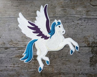 Puede incluir: Parche blanco bordado de un pegaso con alas moradas y una crin y cola azules. El pegaso está en una pose de vuelo con las patas extendidas.