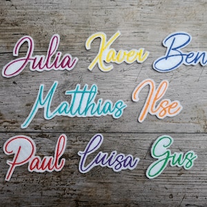 May include: Eight colorful embroidered name patches with names including Julia, Kaver, Ben, Matthias, Ilse, Paul, Luisa, and Gus.