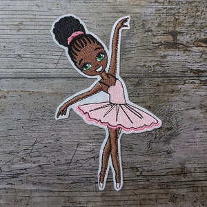 Könnte beinhalten: Ein gestickter Bügelaufkleber mit einer Ballerina mit brauner Haut, grünen Augen und einem rosa Tutu.