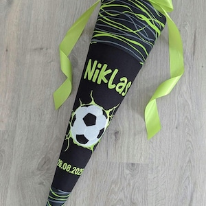 Könnte beinhalten: Ein schwarzer und grüner Schultüte mit einem Fußball-Design. Die Tüte hat den Namen "Niklas" und das Datum "28.08.2023" aufgedruckt.