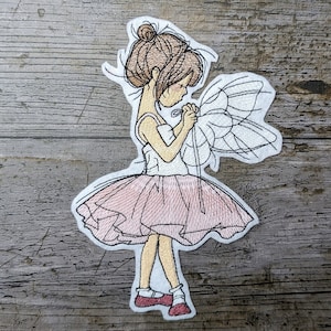 May include: Embroidered patch of a ballerina girl with brown hair, wearing a pink tutu and red shoes. She is holding a white tulle fabric in her hands.