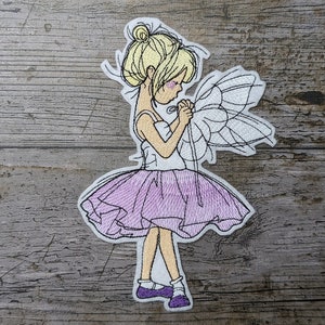 Puede incluir: Parche bordado para planchar de una niña con un tutú morado sosteniendo una mariposa blanca.