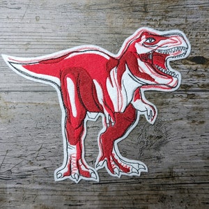 May include: Red embroidered iron-on patch of a Tyrannosaurus Rex dinosaur with white stitching.