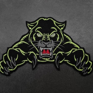 May include: Black and green embroidered patch of a snarling panther with sharp claws. The panther's eyes are black and its mouth is open, revealing red teeth.