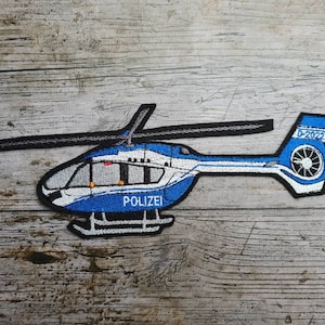 Puede incluir: Un parche de helicóptero azul y blanco con el texto "POLIZEI" y "D-2022" bordado.