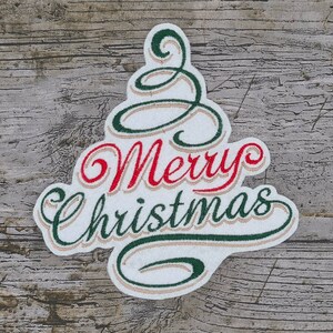 Könnte beinhalten: Weißer Filz-Weihnachtsbaum-Anhänger mit grüner und roter Stickerei mit der Aufschrift "Frohe Weihnachten".