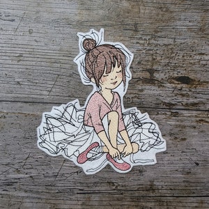 Op de afbeelding: Geborduurde patch van een jong meisje in een roze jurk en een witte tutu, die haar roze balletten bindt.