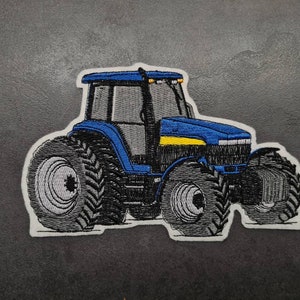 Peut inclure: Patch brodé représentant un tracteur bleu et jaune. Le tracteur a de grandes roues et un design détaillé.