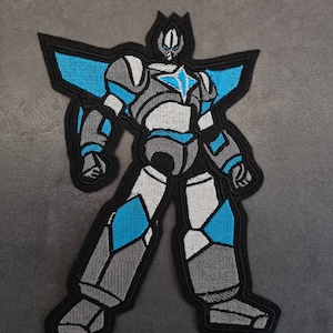 Puede incluir: Un parche bordado de un robot, con colores azul y gris, con una estrella en el pecho.
