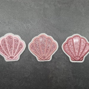 May include: Three pink glitter seashell patches with white outlines.