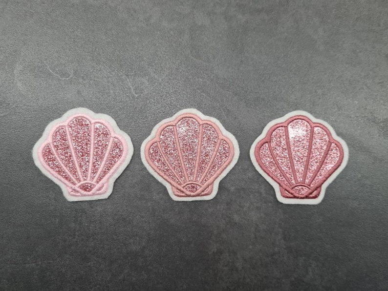 May include: Three pink glitter seashell patches with white outlines.