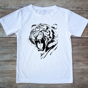 Pode incluir: Uma camiseta branca com um gráfico preto e branco de uma cabeça de tigre rugindo.