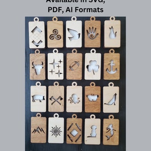 Könnte beinhalten: Ein Satz von 20 lasergeschnittenen Holz-Etiketten mit verschiedenen Designs, darunter ein Stier, eine Taube, eine Hand, eine Katze, Sterne, ein Fußball, ein Kleeblatt, ein Anker, ein Schwein, gekreuzte Äxte, ein Tintenfisch, ein Schmetterling, ein Wolf, Berge, eine Sonne, eine Raute, ein Hund und eine Meerjungfrau. Die Etiketten sind in vier Reihen mit jeweils fünf Etiketten angeordnet. Die Etiketten sind alle aus hellem braunem Holz gefertigt und haben eine natürliche Oberfläche.