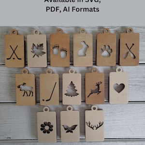 Könnte beinhalten: Ein Set aus 15 lasergeschnittenen Holz-Tags mit verschiedenen Designs, darunter ein Hockeyschläger, ein Ahornblatt, Bärenpfotenabdrücke, ein Kaninchen, ein Pfotenabdruck, ein Herz, ein Elch, ein Hockeyschläger, ein Weihnachtsbaum, ein Reh, eine Blume, ein Schmetterling und Geweih. Die Tags sind in den Formaten SVG, PDF und AI verfügbar.