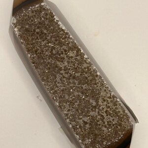 May include: A polished crystal point with a brown and gray banded exterior. The center of the crystal is covered in small, sparkling, light brown crystals. The crystal is rectangular with a pointed top.