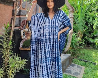 Op de afbeelding: Een blauwe en witte tie-dye kaftan met een V-hals en lange mouwen. De kaftan wordt gedragen door iemand met een brede zwarte hoed.