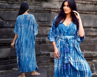 Op de afbeelding: Een lange, blauwe en witte tie-dye kaftan met een V-hals en een ceintuur om de taille. De kaftan heeft een losse pasvorm en is perfect voor een strandvakantie of een casual zomeroutfit.