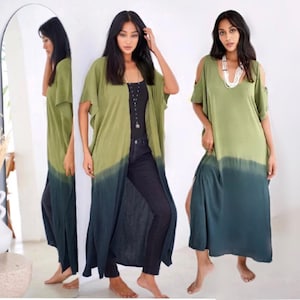 May include: A long, flowing dress and a matching open-front cardigan in a two-tone color scheme. The top portion is olive green, transitioning to a deep teal at the bottom. The dress features cold-shoulder sleeves and a side slit.