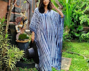 Op de afbeelding: Een wit-blauwe kaftan met een tie-dye patroon. De kaftan heeft een V-hals en is gemaakt van een lichtgewicht stof.