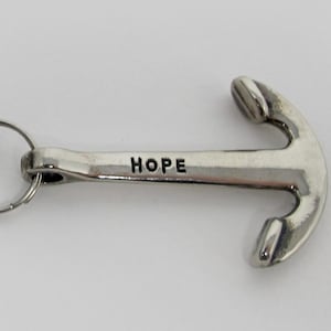 May include: Silver-colored anchor keychain with the word "HOPE" engraved on the anchor. The keychain includes a large ring, a chain, and a smaller ring connecting to the anchor. The anchor design is detailed and three-dimensional.