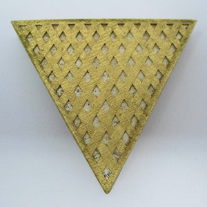 May include: A gold triangular brooch with a diamond pattern cut-out design.