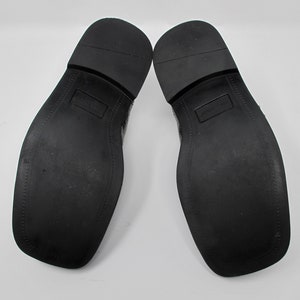 May include: A pair of black leather dress shoes with a textured pattern on the upper. The shoes have a black rubber sole.