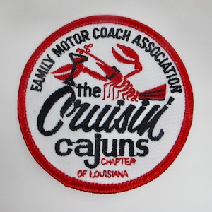 May include: Circular patch with a red border and white center. The patch features a red crawfish illustration and the text "Family Motor Coach Association" and "the Cruisin' Cajuns Chapter of Louisiana" in black.